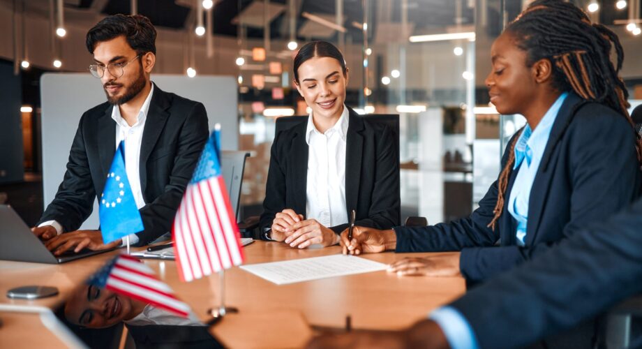 The flags of the USA and the European Union are on the table during negotiations between diplomats and businessmen. Representatives discuss relations between countries, signing a treaty.