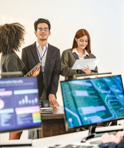 Multiethnic AI security squad analyzing threat intelligence in a bright SOC. Diverse IT experts collaborating on machine learning defense behind blurred data dashboards.