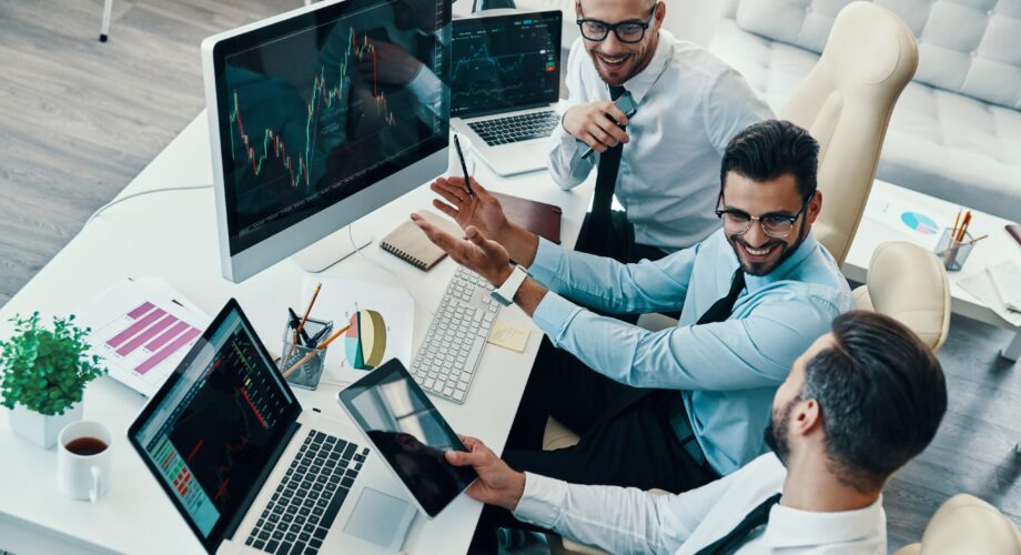 Achieving best results together. Top view of young modern men in formalwear analyzing stock market data and smiling while working in the office