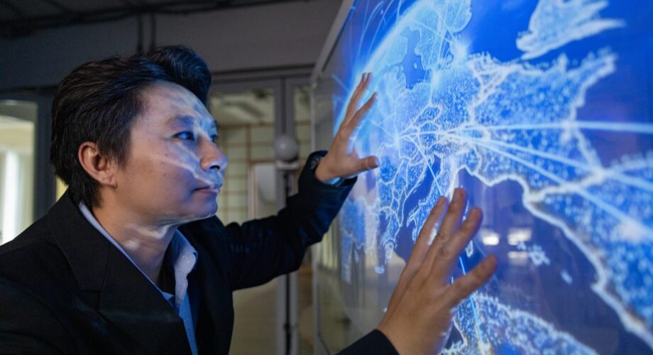 A professional man interacts with a high-tech circular data interface on a large digital screen, featuring graphs and data elements in a glowing blue theme.